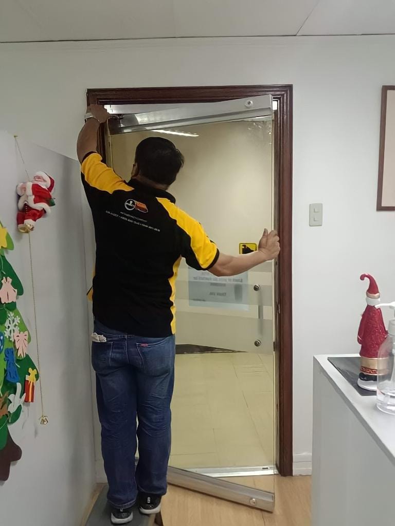 Dokey locksmith technician working on a commercial glass-door frame.