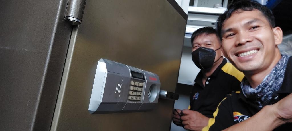 Dokey technicians beside a large safe with an electronic lock.